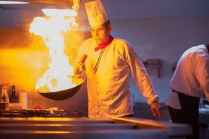 kock håller på med flambe på mat foto