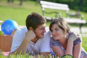 Lycklig ung par har en picknick utomhus- foto