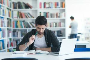 studerande i skola bibliotek använder sig av bärbar dator för forskning foto