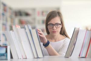 porträtt av famale studerande väljer bok till läsa i bibliotek foto