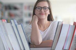 porträtt av famale studerande väljer bok till läsa i bibliotek foto