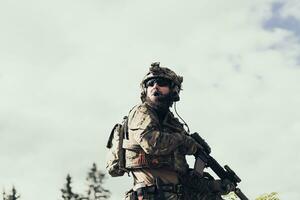 krig begrepp. en skäggig soldat i en särskild krafter enhetlig stridande ett fiende i en skog område. selektiv fokus foto