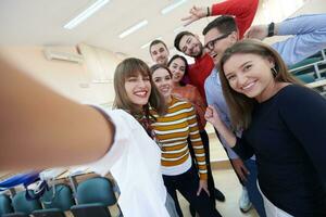 grupp av multietnisk tonåringar tar en selfie i skola foto