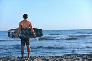 porträtt av en ung kitsurf man på strand på solnedgång foto