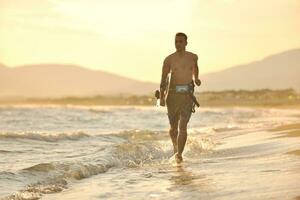 porträtt av en ung kitsurf man på strand på solnedgång foto