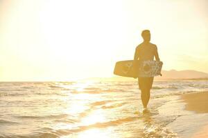 porträtt av en ung kitsurf man på strand på solnedgång foto