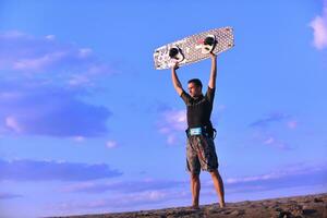 porträtt av en ung kitsurf man på strand på solnedgång foto