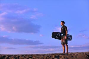 porträtt av en ung kitsurf man på strand på solnedgång foto