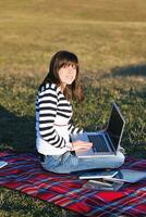 ung tonåring flicka arbete på bärbar dator utomhus foto