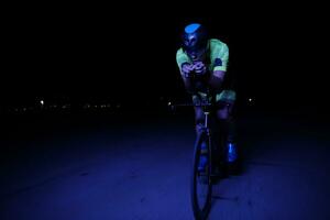 triathlonatlet som cyklar snabbt på natten foto