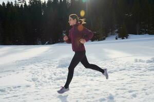 yougn kvinna joggning utomhus- på snö i skog foto