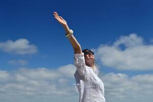 glad ung kvinna med utspridda armar mot himlen foto
