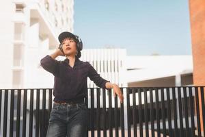 glad ung asiatisk kvinna som lyssnar på musik med hörlurar
