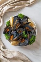 musslor med örter i en skål med citron foto