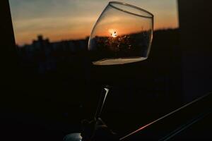 glas av röd vin med Sol inuti foto