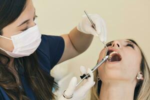 stänga upp skott av tandläkare administrering anestesi till kvinna patient. foto
