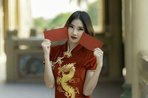 porträtt vacker asiatisk kvinna i cheongsam klänning, thailändska människor, gott kinesiskt nyårs koncept, glad asiatisk dam i traditionell kinesisk klänning foto