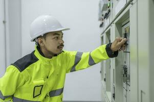 elektrisk ingenjör man kontroll Spänning på de kraft distribution skåp i de kontrollera rum, förebyggande underhåll årligen, thailand elektriker arbetssätt på företag foto