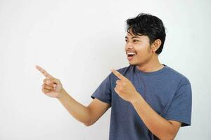 leende eller Lycklig stilig ung asiatisk man med hans finger pekande isolerat på vit bakgrund med kopia Plats foto