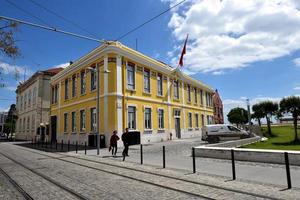 Lissabon, Portugal - 26 april 2019, turister går förbi en gul byggnad foto