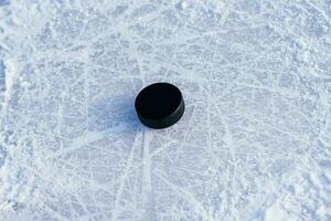 svart hockey puck lögner på is på stadion foto