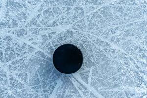 svart hockey puck lögner på is på stadion foto