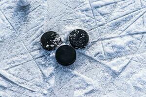 svart hockey puckar lögner på is på stadion foto