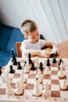 liten pojke spelar schack på Hem på de tabell foto