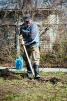 en man är plantering en ung träd. de jordbrukare är grävning de jord med en skyffel för en små fröplanta. de begrepp av skydd av de miljö och ekologi foto