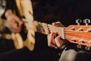 man spelar akustisk gitarr och spelar ackord närbild foto