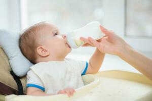 mor matar bebis från en flaska av mjölk foto
