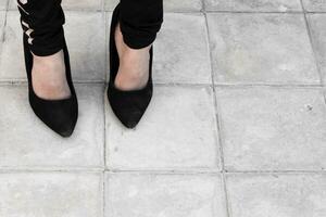 12 år gammal flicka bär mor stor skor. en liten flicka i svart överdimensionerad hög häl skor foto