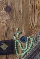 traditionell muslim bön uppsättning bunt. bön- matta, radband pärlor, liten version av de helig quran och qibla kompass på trä- bakgrund. fri Plats foto