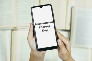 internationell kunnighet dag på smartphone skärm över böcker bakgrund foto