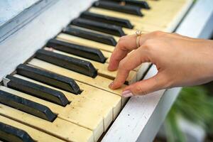 de händer av flicka på de gammal piano nycklar. Foto piano i retro stil.