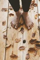 de fötter av de person på de trä- golv täckt med falla löv. höst säsong begrepp med kopia Plats foto