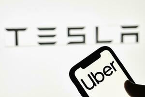 en person innehar smartphone med uber varumärke med tesla logotyp foto