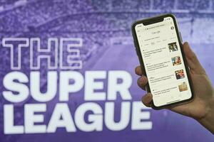 hand innehav smartphone med Nyheter över de super liga logotyp foto