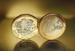 1 pund och 1 euro mynt över metall bakgrund foto