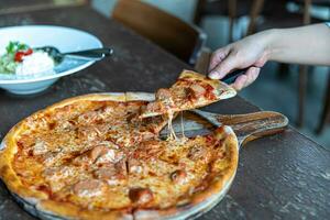 pepperoni pizza med mozzarella ost, salami, tomater, peppar, kryddor och färsk basilika. italiensk pizza. pizza skiva på trä maträtt foto