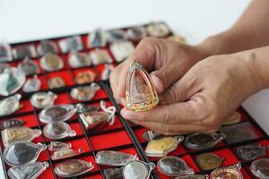 närbild hand innehar thai buddha amulett från amulett samling. begrepp, tro och tro för buddist för helig och tur. insamling amulett som hobbyer, utbyta, försäljning eller uppköp foto