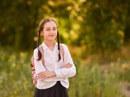 ung skolflicka med ryggsäck. utomhus höst park. tillbaka till skolan foto