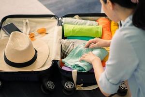 asiatisk kvinna ordnar kläder i resväskan för att förbereda sig för resor foto