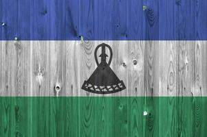 lesotho flagga avbildad i ljus måla färger på gammal trä- vägg. texturerad baner på grov bakgrund foto