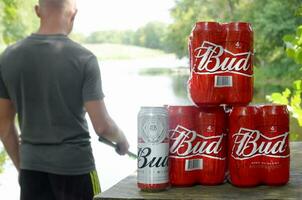 budweiser knopp öl burkar packa på gammal tabell och fiskare på flod på bakgrund foto