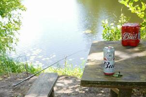 budweiser knopp öl burkar på gammal trä- tabell utomhus på de flod och grön träd bakgrund foto