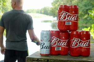 budweiser knopp öl burkar packa på gammal tabell och fiskare på flod på bakgrund foto