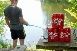 budweiser knopp öl burkar packa på gammal tabell och fiskare på flod på bakgrund foto