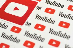 Youtube logotyp klistermärke på mönster tryckt på papper med små Youtube logotyper och inskriptioner. Youtube är Google dotterföretag och amerikan mest populär videodelning plattform foto