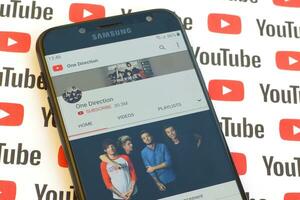 ett riktning officiell Youtube kanal på smartphone skärm på papper Youtube bakgrund. foto